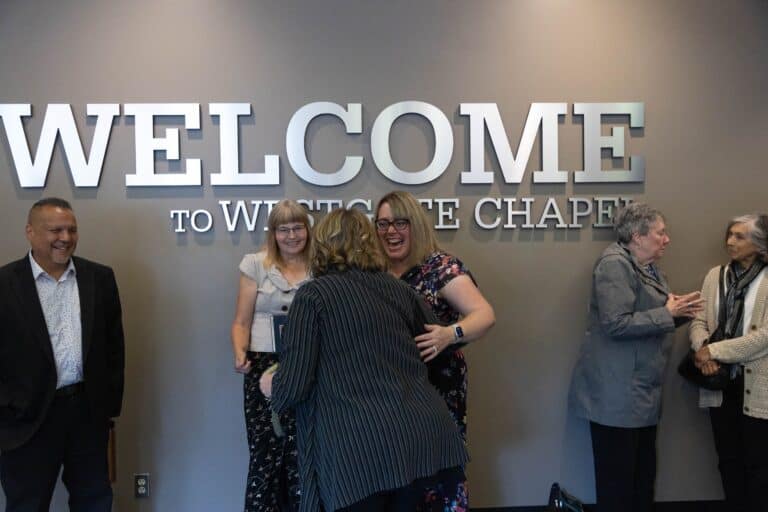 A diverse group of individuals standing in front of a welcome sign at Westgate Chapel, a nondenominational church in Edmonds, WA.