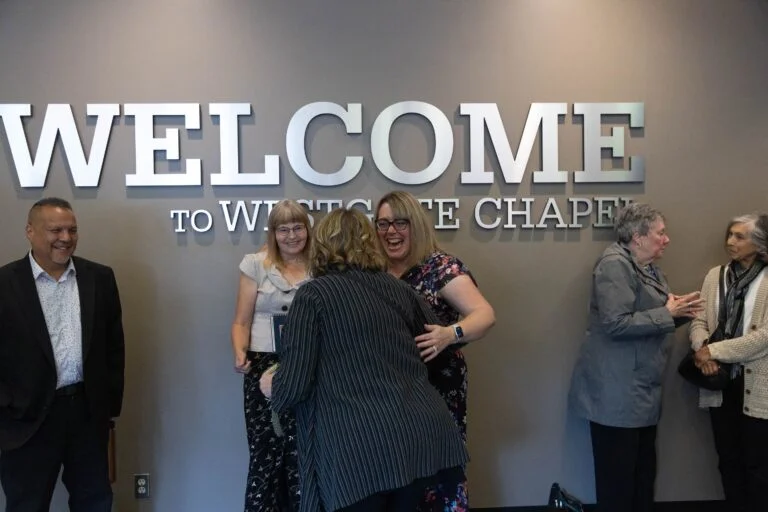 A diverse group of individuals standing in front of a welcome sign at Westgate Chapel, a nondenominational church in Edmonds, WA.
